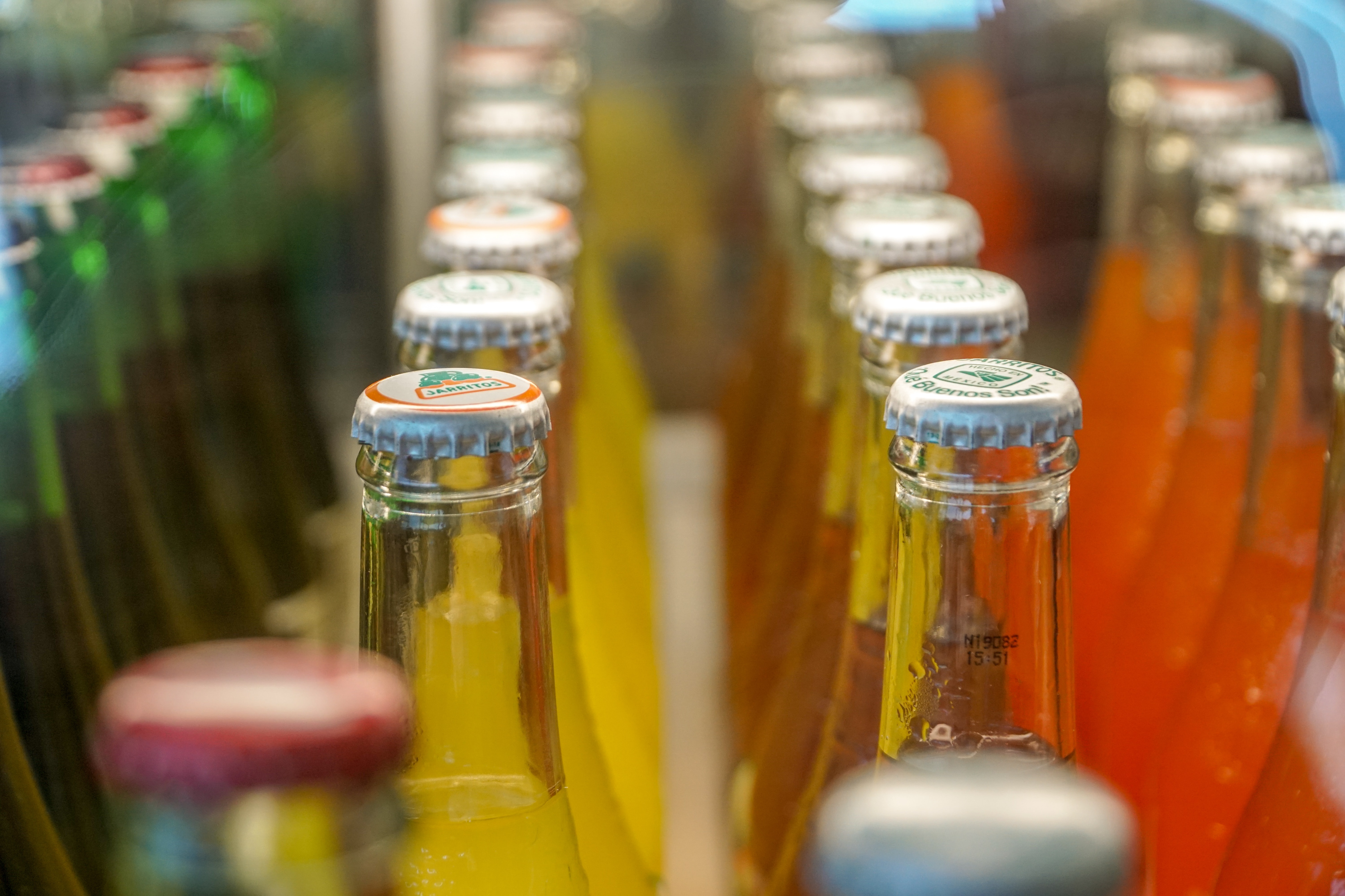 A close-up of colored soda bottles in a production line