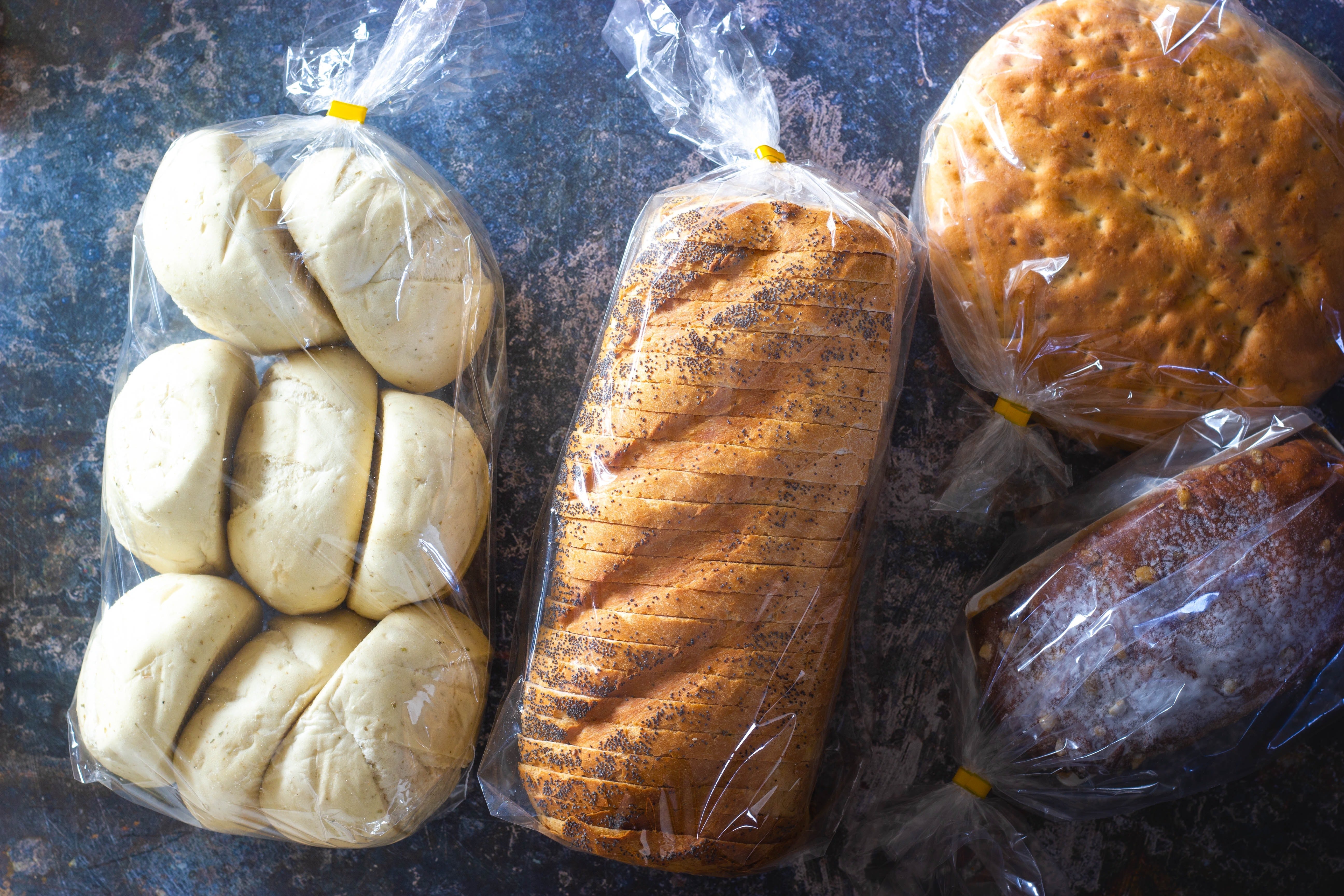Four packets of different bread laid on a worktop counter