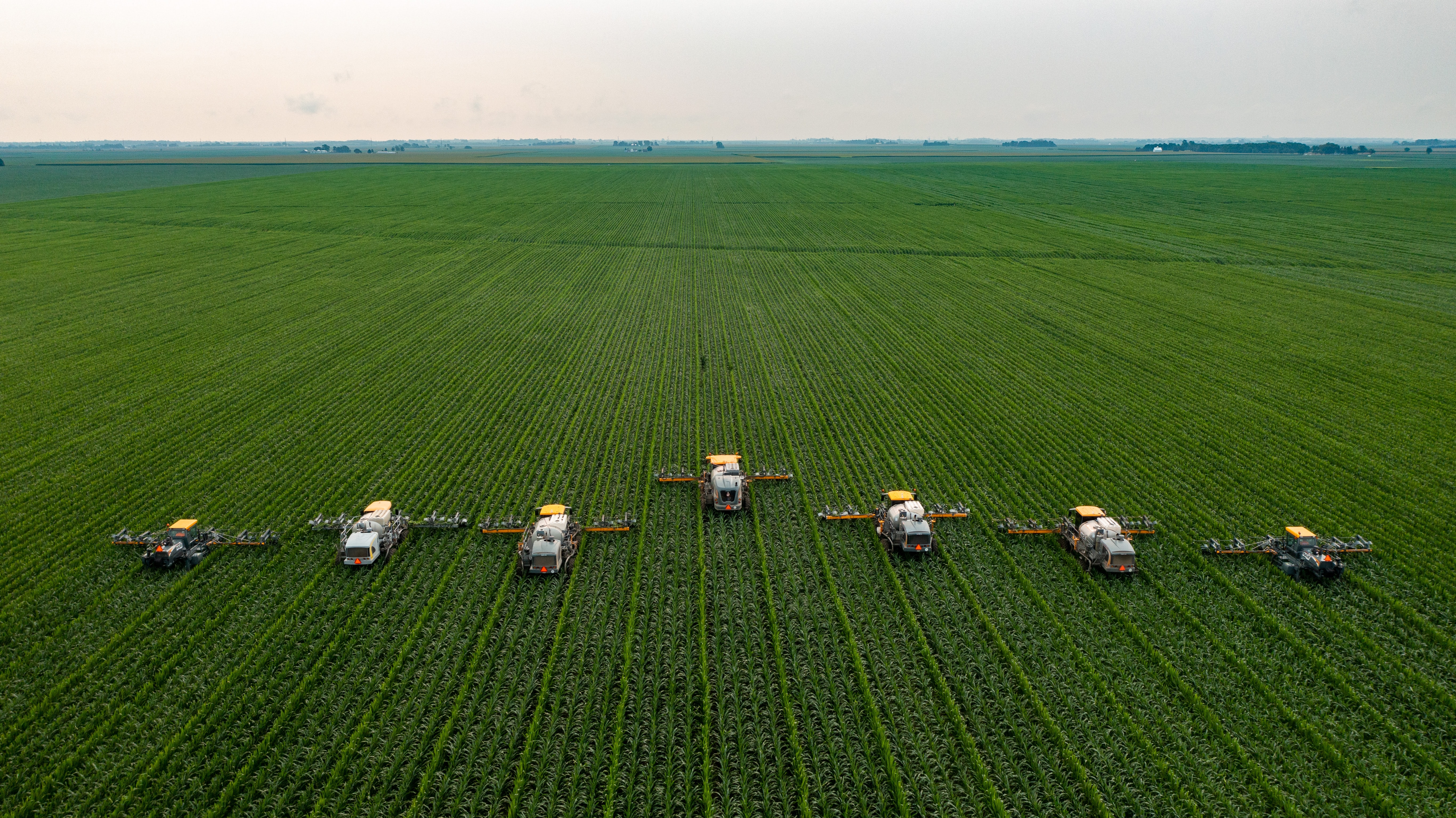 Seven harvesting machine work their way through a crop field