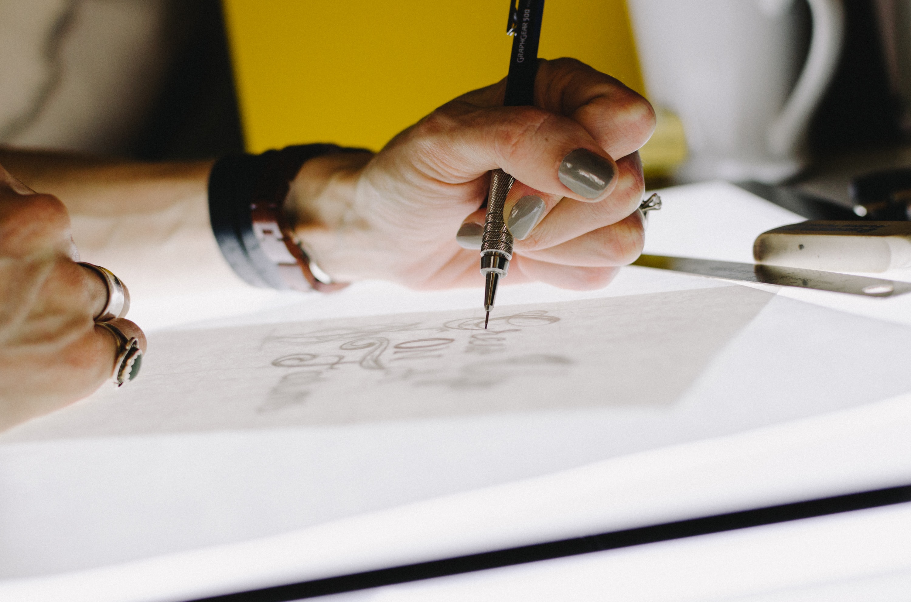 A close up for a packaging designer's hands, hand-drawing typography on a light box