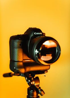 Canon camera on a tripod with a bright yellow background