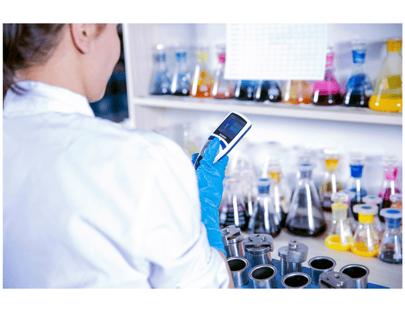 Scientist in front of a shelf of chemical beakers full of colorful liquid