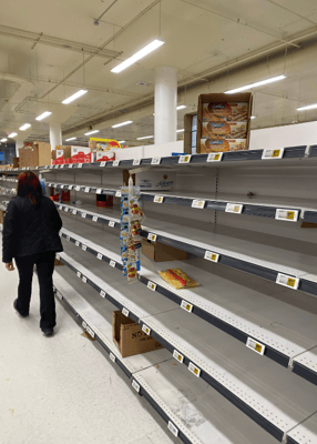 Person walking past empty shelves in a retail store