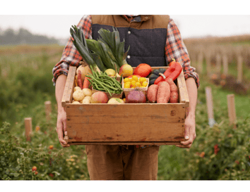 Farmer in a field holding a box of colorful produce