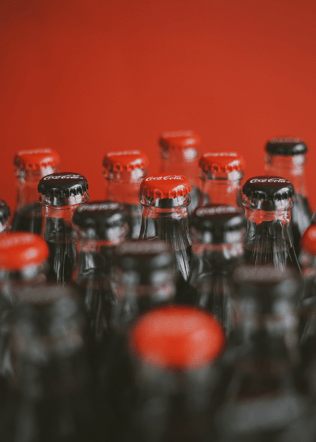 Tops of glass bottles of coca cola with a red background