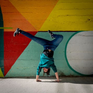 A woman doing a handstand against a rainbow-colored wall