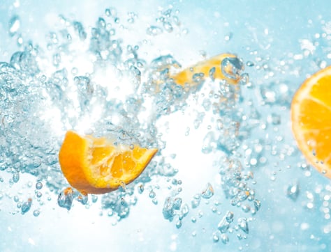A close up of fruit segments splashing with water