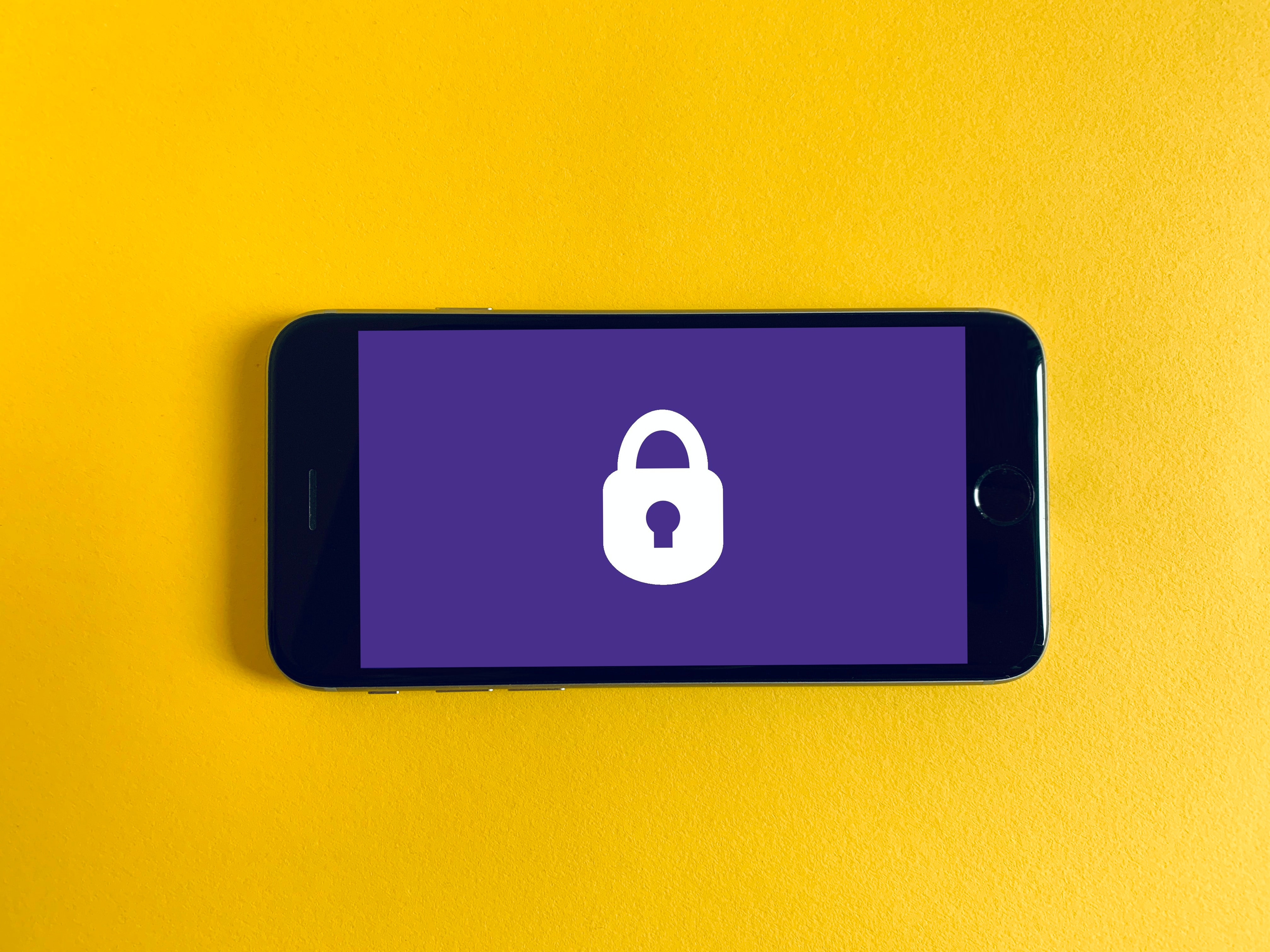 A smart phone shown against a yellow background, displaying a purple image with a white padlock icon