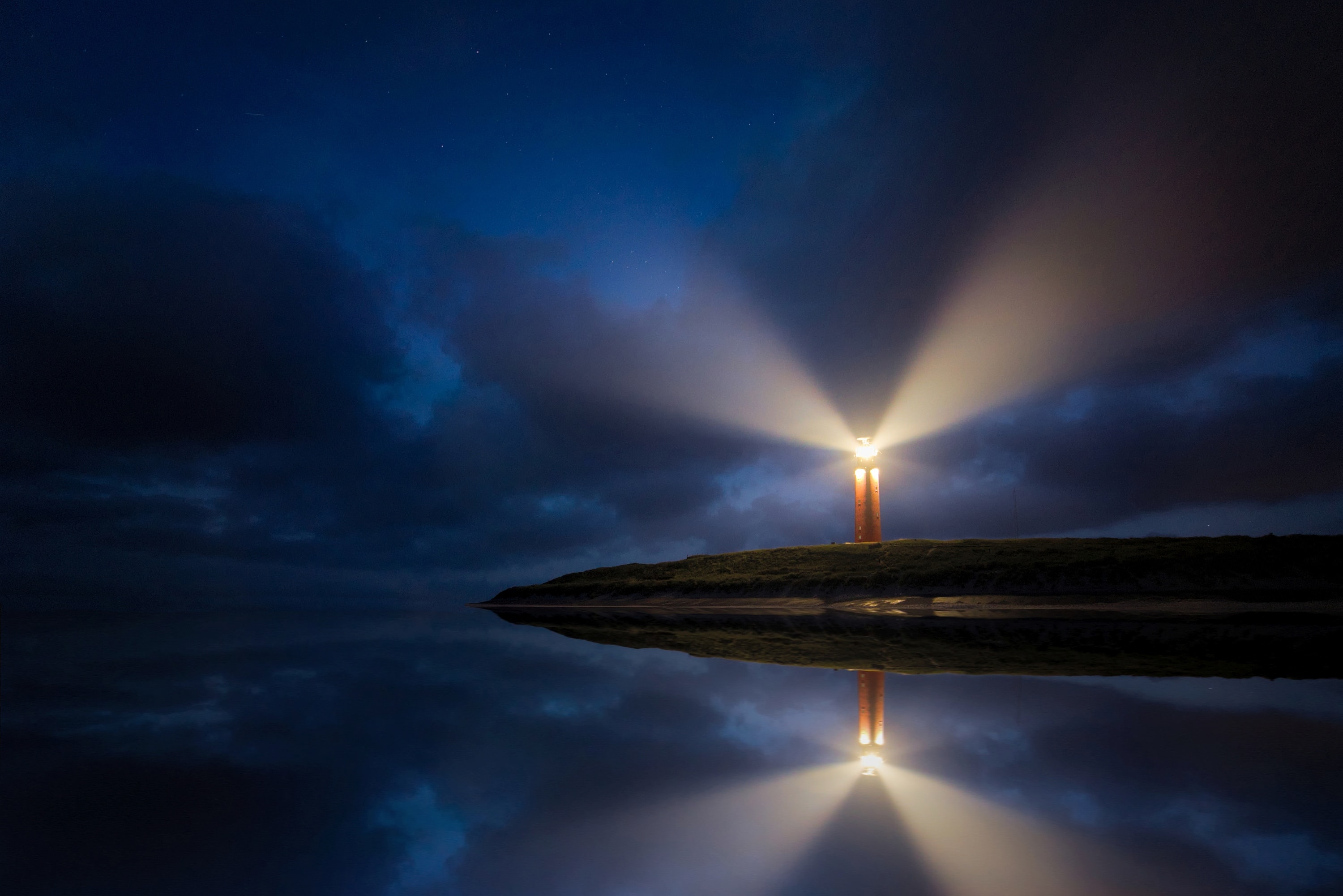 An image of a lighthouse at night, emitting a bright light beacon