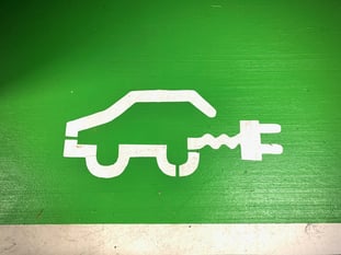 An electric vehicle charging port sign — an illustration of an electric car painted in white on a green wall
