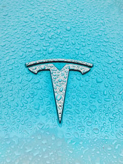 Close up of a Tesla logo, on a bright blue electric car