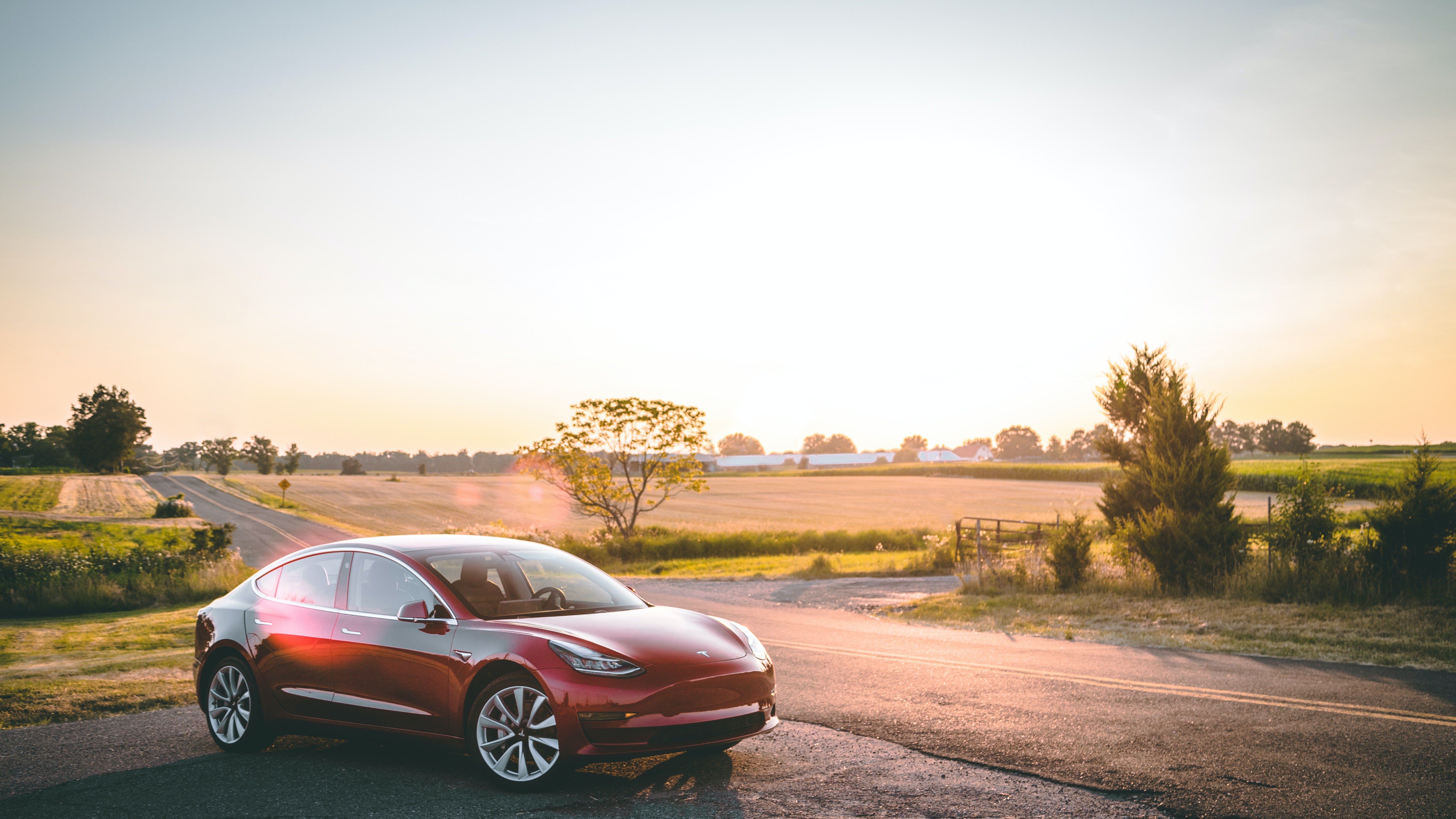 A Tesla electric car parked up by the side of a country road