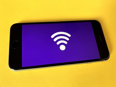 A smartphone screen with the WiFi logo against a yellow background