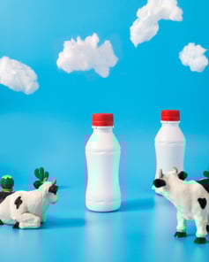 A staged backdrop with model clouds, model cows and a small milk bottle in the center