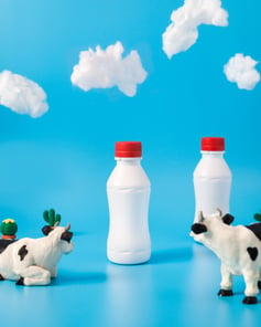 A staged backdrop with model clouds, model cows and a small milk bottle in the center