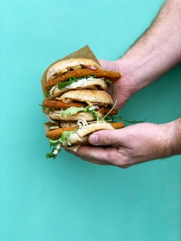 A man holds a triple-stacked veggie burger