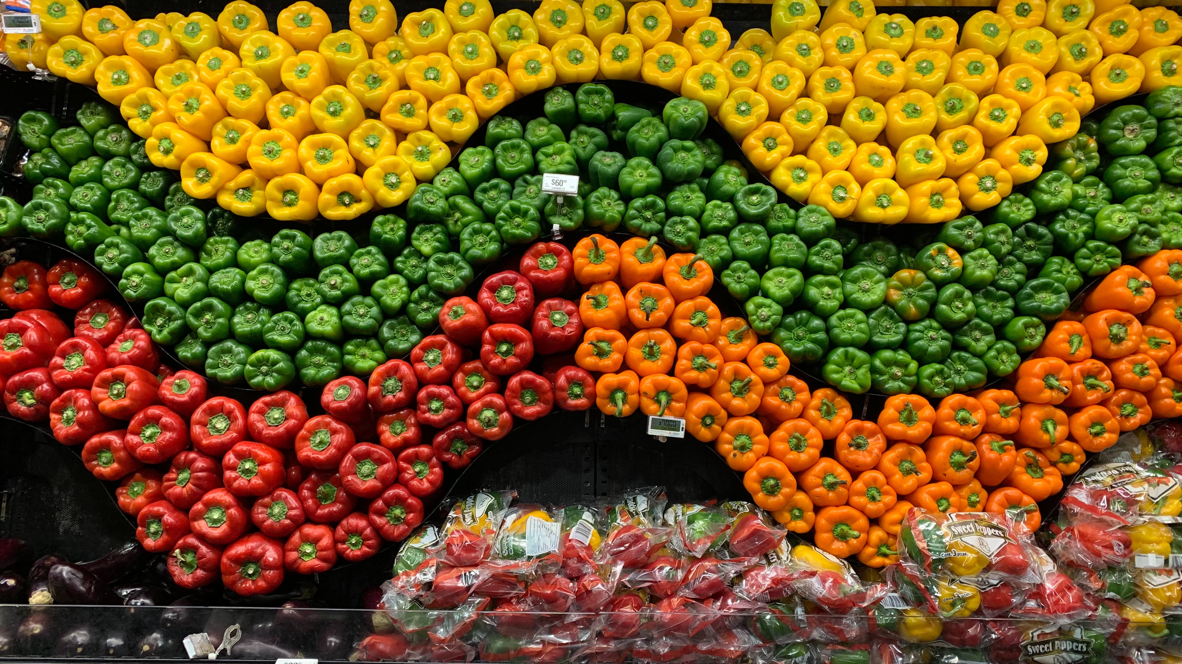 An example of grocery store merchandising using the power of three: stacks of bell peppers in red, yellow and green