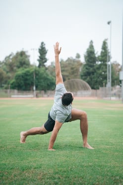 A man does yoga on a recreational field
