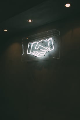 A white neon sign of a handshake