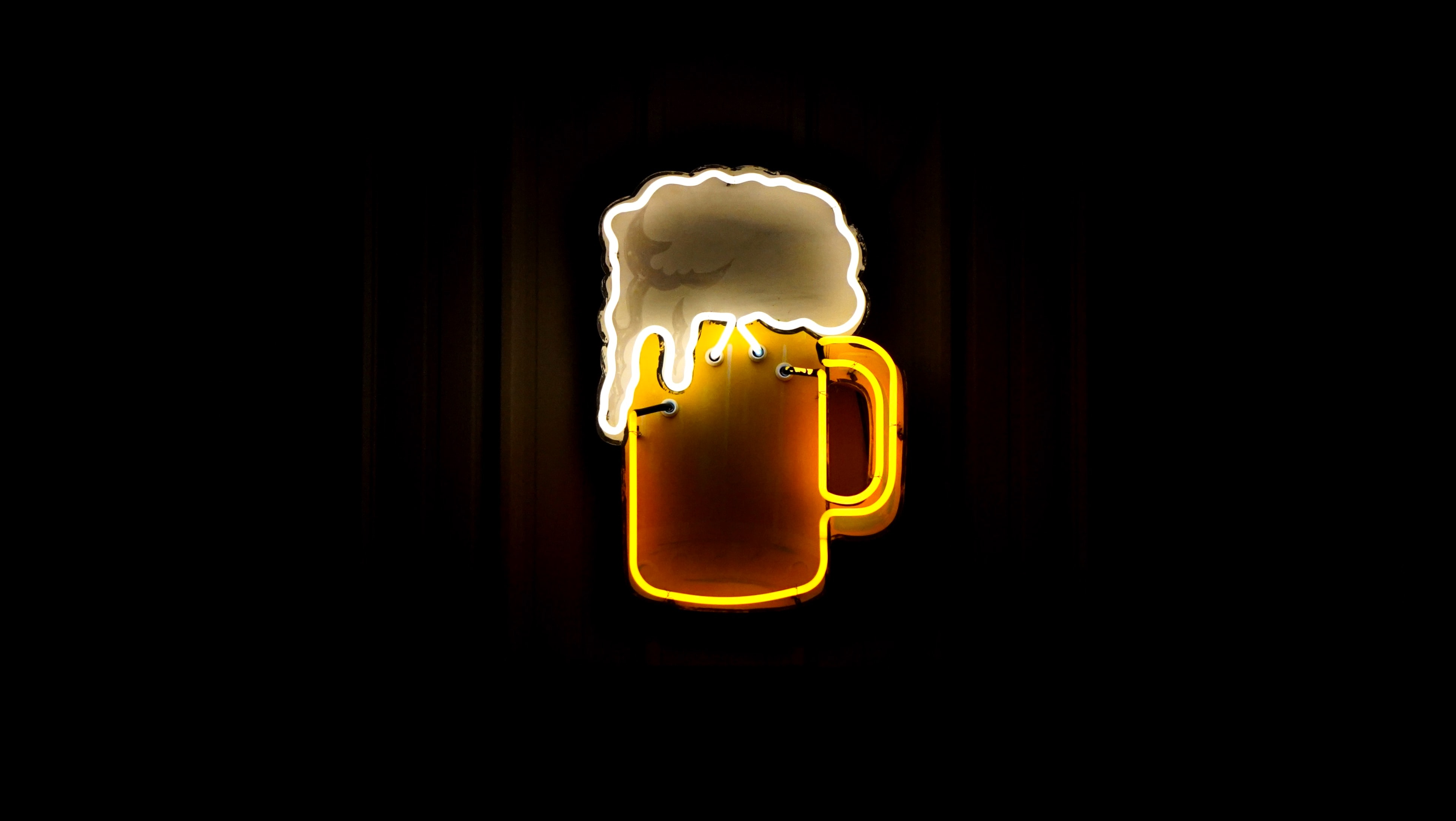 A neon wall sign of a cartoon beer with a foamy head