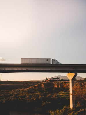 A food distribution truck drives over a bridge at sunrise