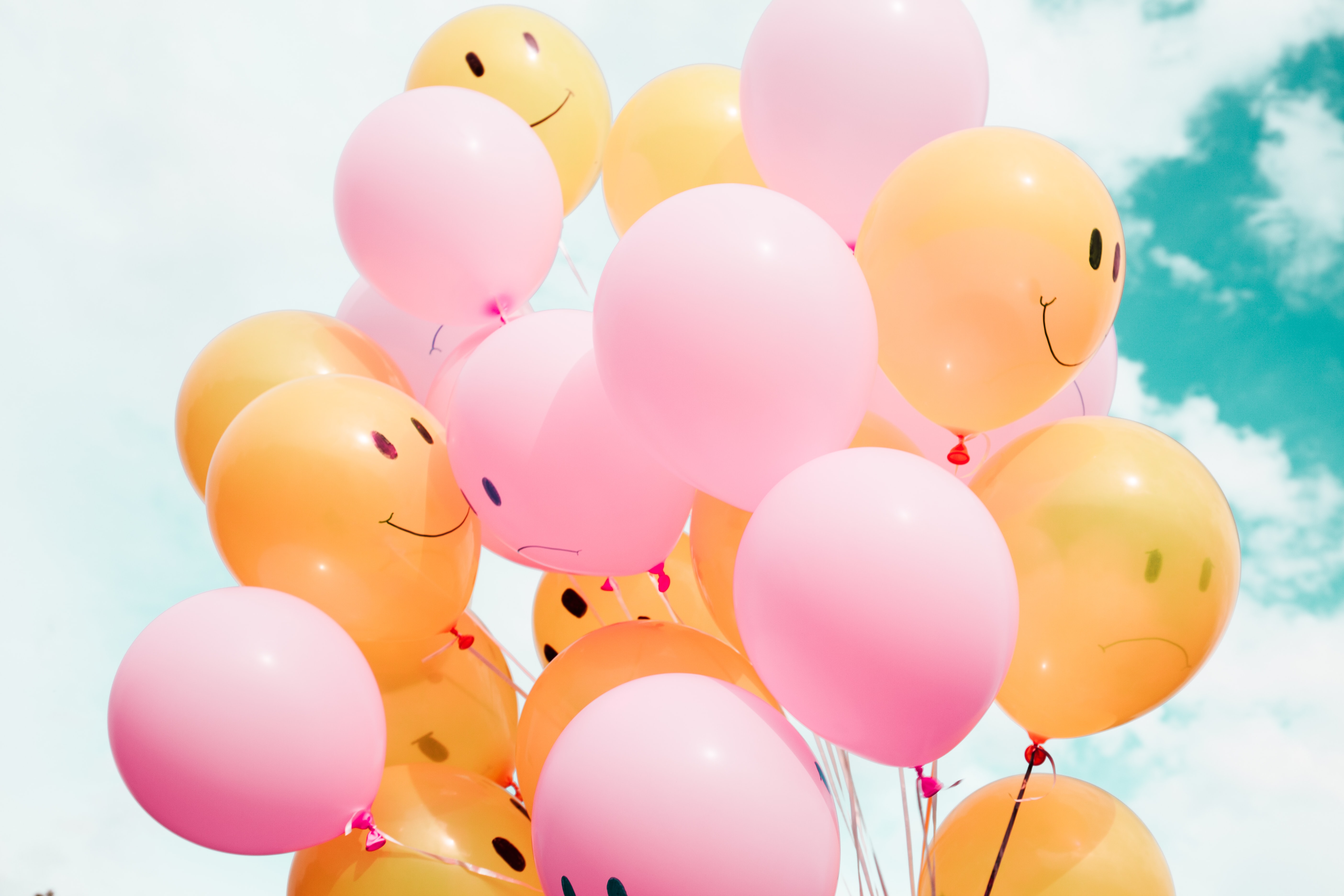 A bunch of yellow and pink balloons with happy and sad faces