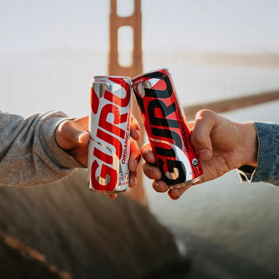 Guru energy drink cans cheersing with the Golden Gate Bridge in the background