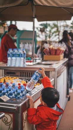 A child grabbing a bottle of water from a cart.