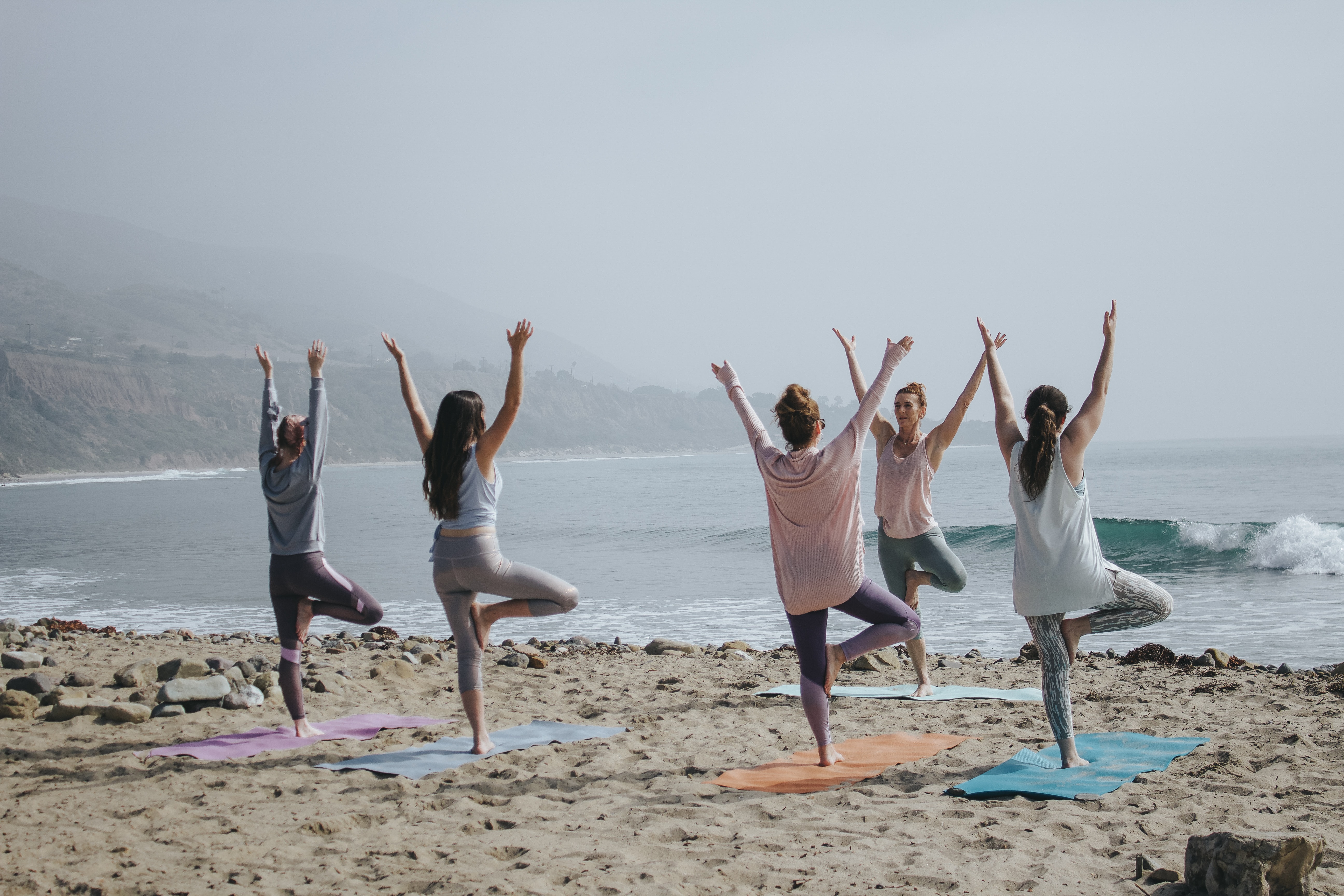 A group doing yoga on the beach.