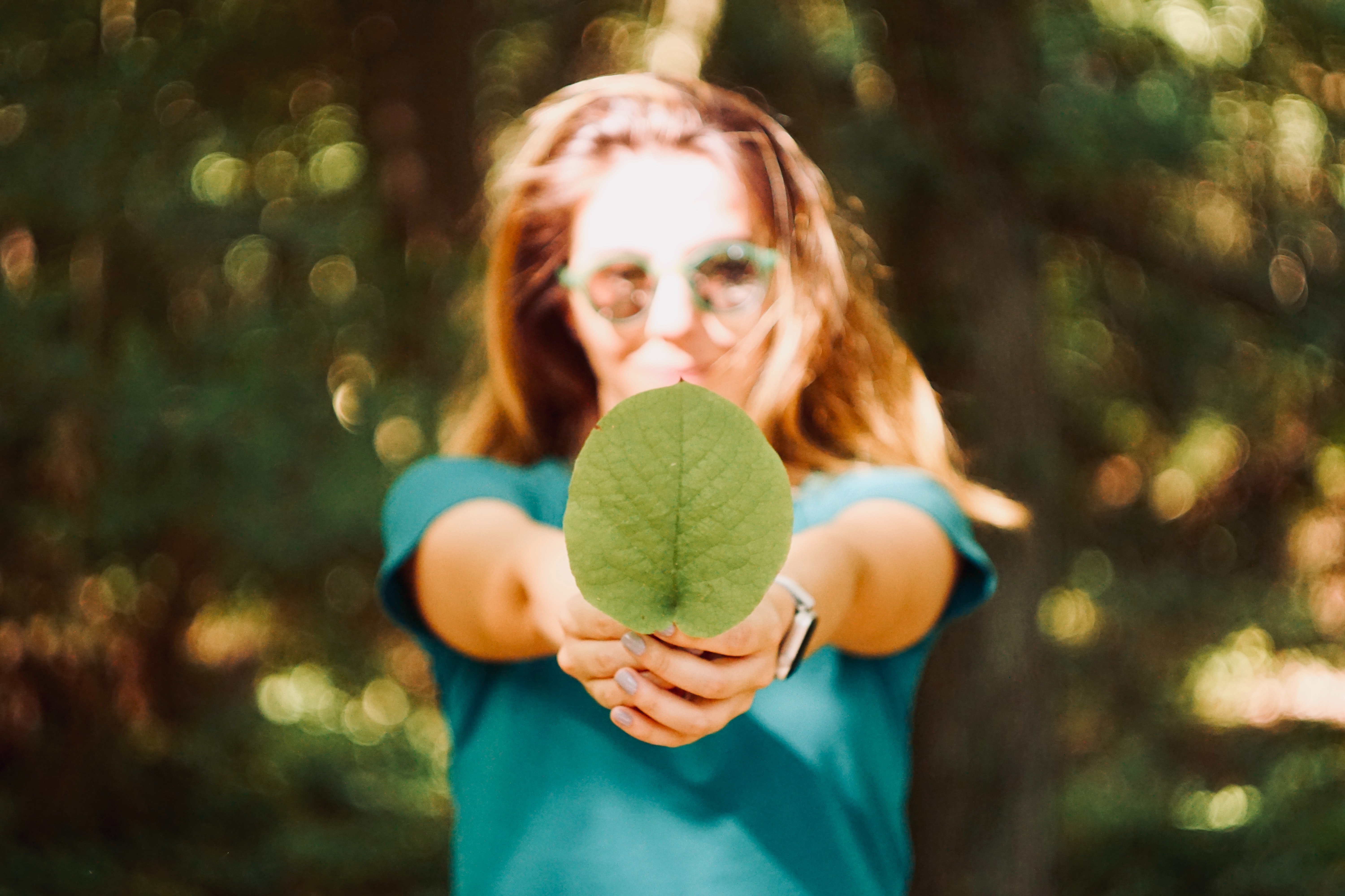 A woman holds a leaf out to the camera.