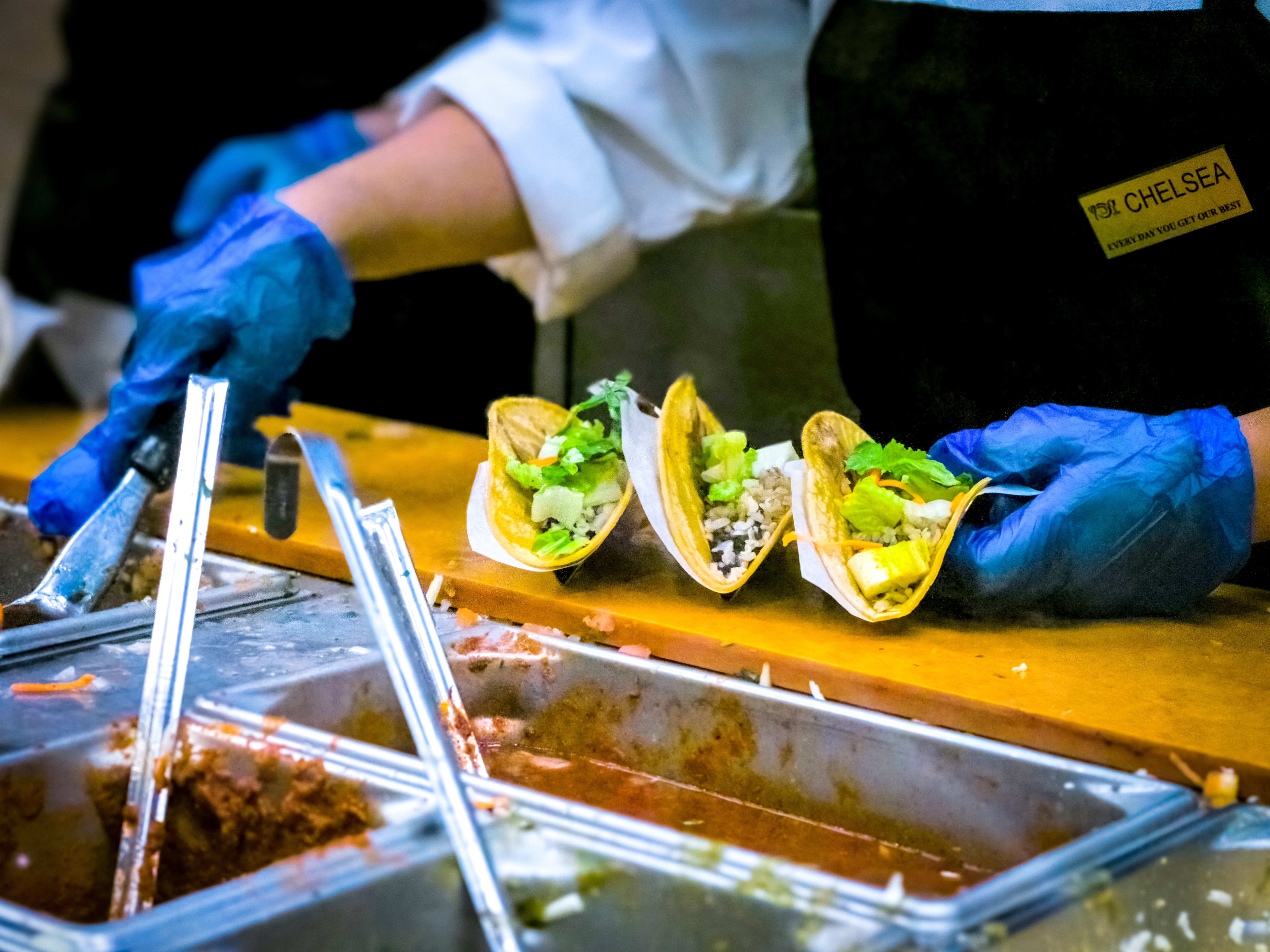 A person in gloves makes tacos.