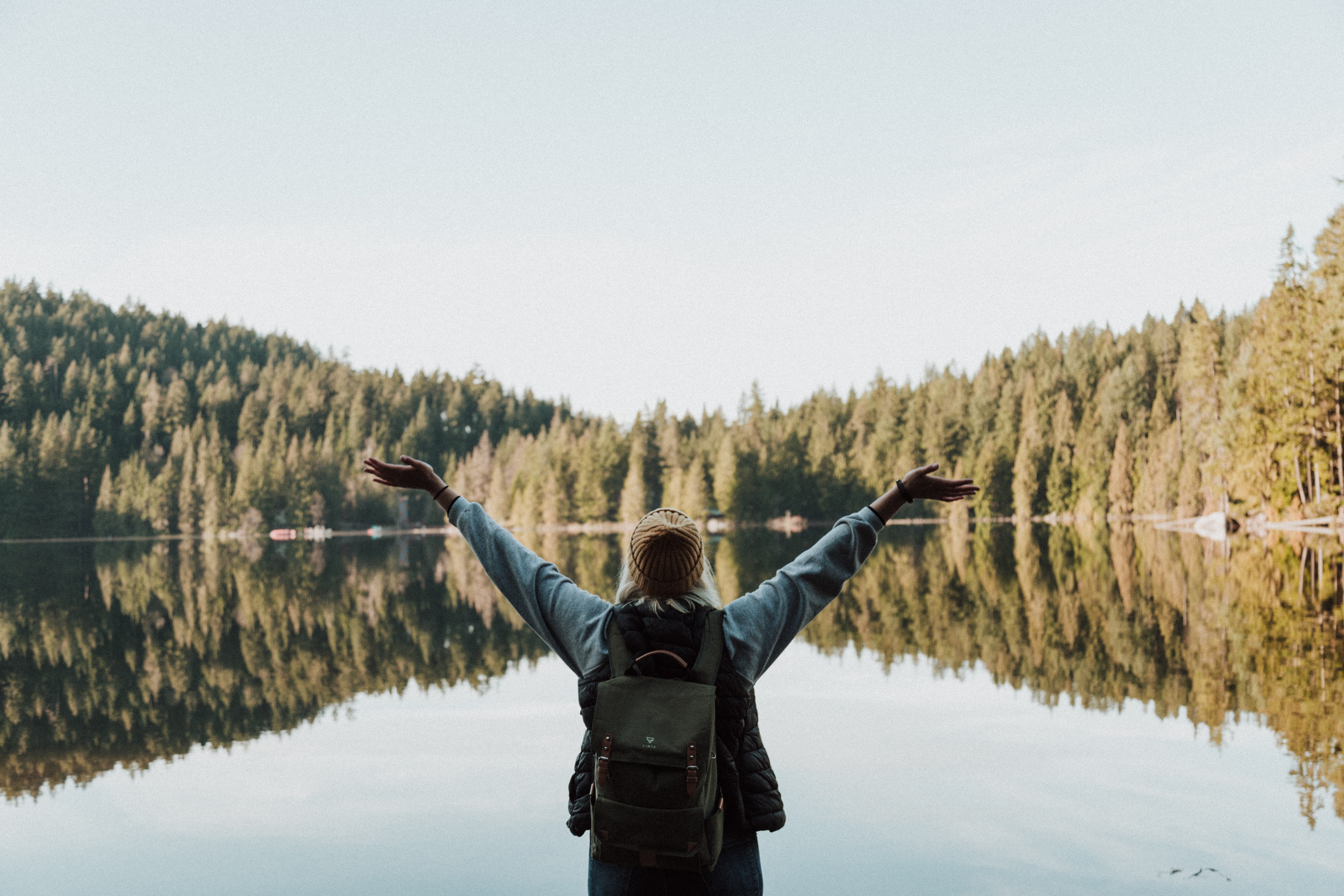 Someone with raised arms by a lake.
