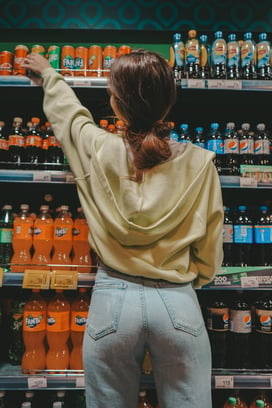 High-touch point merchandising represented by a shopper choosing from beverages in the beverage aisle in a grocery store
