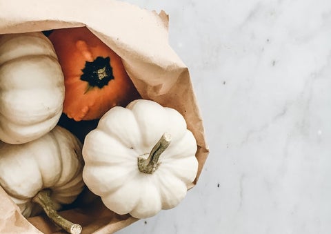 A brown paper bag filled with winter squash