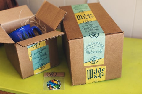 Two cardboard boxes, one open showing a metallic mug