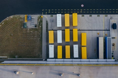 An aerial shot of yellow and white trucks, lined up outside a distribution center