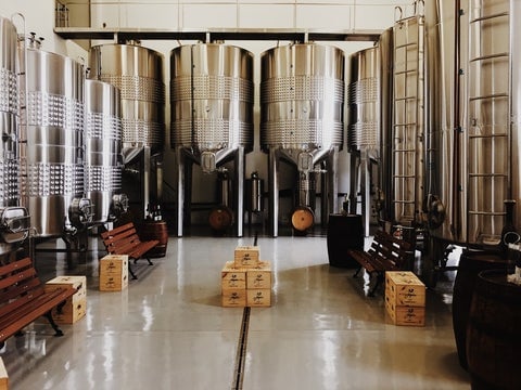 The interior of a brewery with big silver barrels and cardboard boxes scattered on the floor