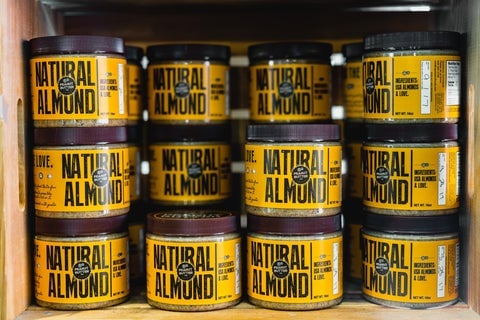 A stack of jars with yellow labels reading 'Natural almond'