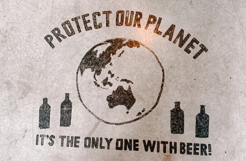 A floor sign that reads 'Protect our plant it's the only one with beer'
