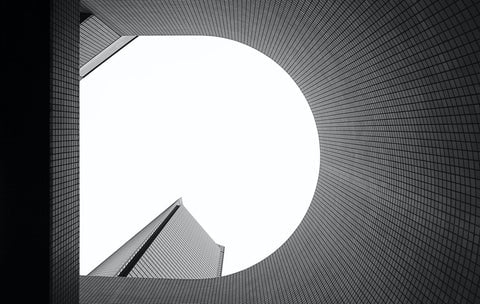 A black and white photo looking up at a building, creating the letter 'D'