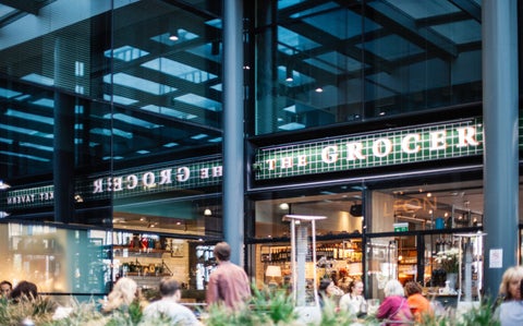 People gather outside a store named 'The Grocer'