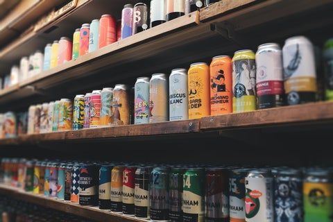 Colorful craft beer cans lined up on a wooden shelf