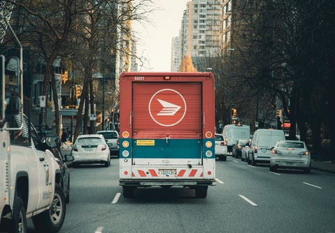 A red, blue, and white van drives through an inner city street