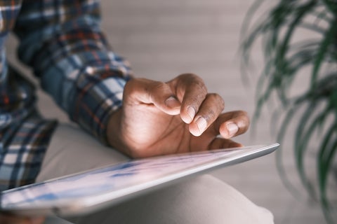 A man holds a tablet on his knee