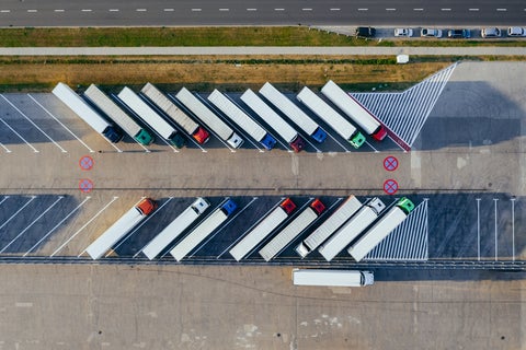 Seen from the sky, a car park of trucks lined up in a row