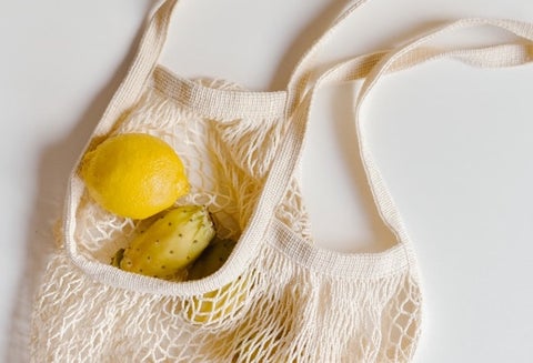 Mixed yellow fruit sits in an eco grocery bag
