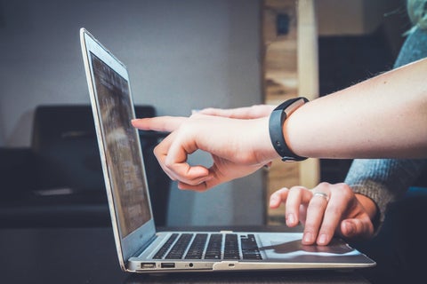 Two people pointing at a laptop screen together