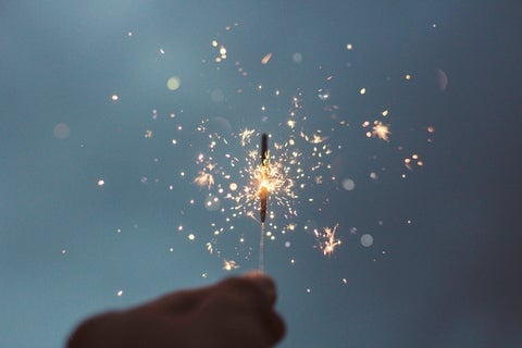 A close-up of a sparkler held against a night sky