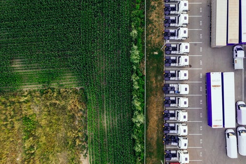A aerial shot of distribution trucks parked in a lot next to a field