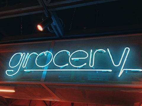 Blue neon sign that reads 'grocery'